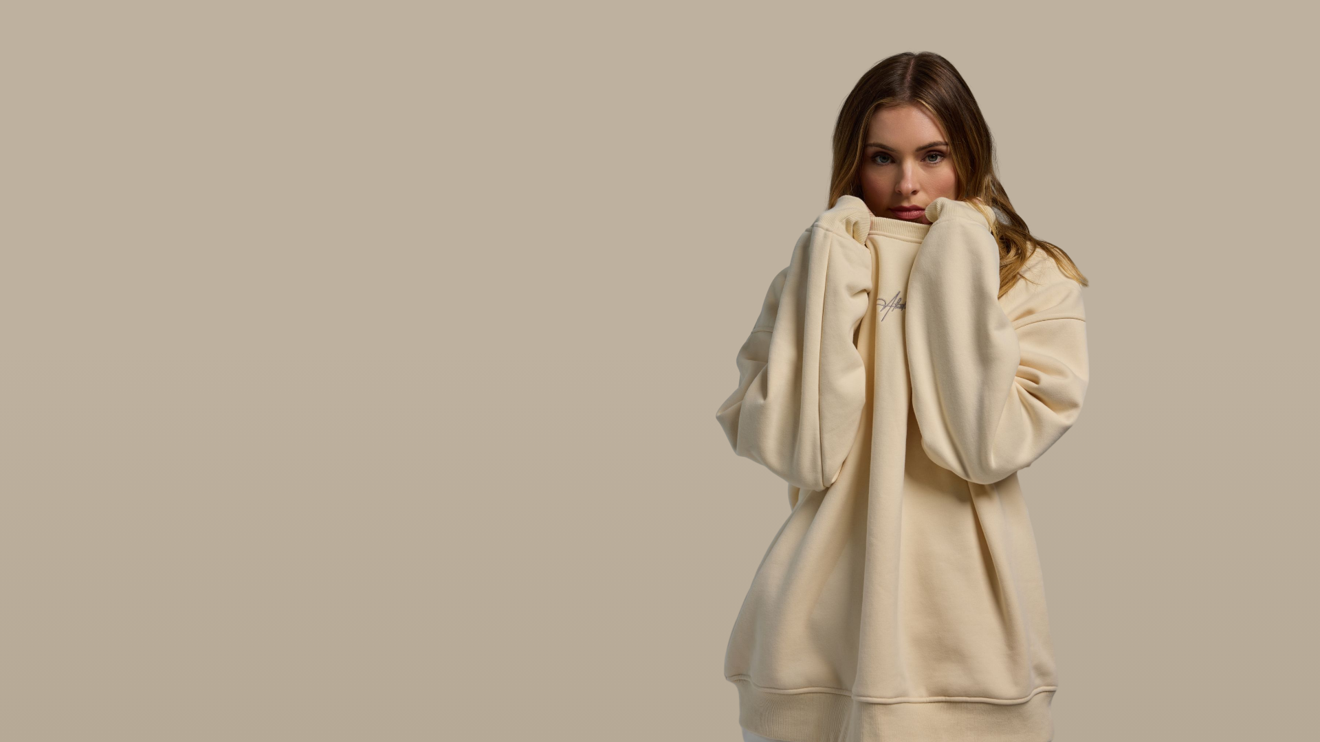 Woman wearing a beige sweater against a plain background